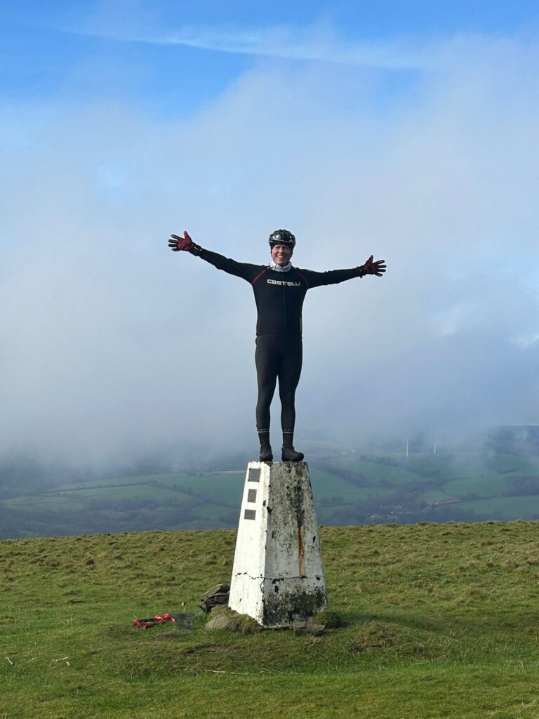 Rob celebrating another successful fire road ascent on top of a trig point
